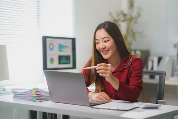 Asian businesswoman using laptop and smiling during video call in office