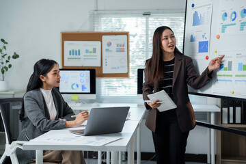 Asian businesswomen discussing and presenting financial chart data at office meeting