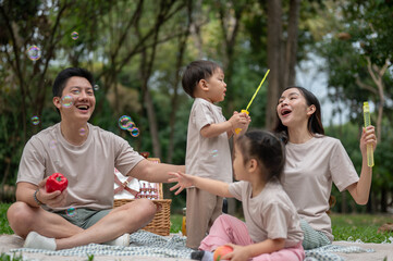 Fototapeta premium A happy Asian family enjoy picnic in a public park together.