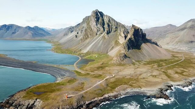 Breathtaking view of Hvalnes in Iceland featuring towering coastal mountains, crystal-clear waters, winding roads, and vibrant green terrain. A perfect representation of Iceland&rsquo;s natural beauty
