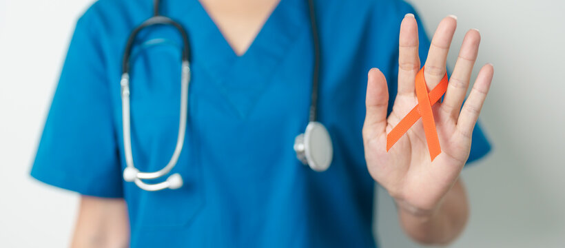Doctor with Orange Ribbon for Leukemia, Kidney cancer day, world Multiple Sclerosis, CRPS, Self Injury Awareness month. Healthcare and word cancer day concept