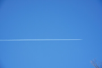 晴天に白線を描いて飛ぶ飛行機