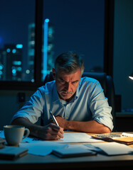 a man sitting at a desk writing in a book