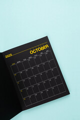 October 2025 Black calendar opening on blue background.