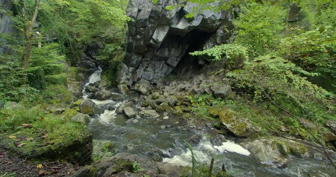 Wide Shot looking across the river sychryd of the rocky over hang. Coed-Y-Rhaidyr, Pontneddfechan, Neath,