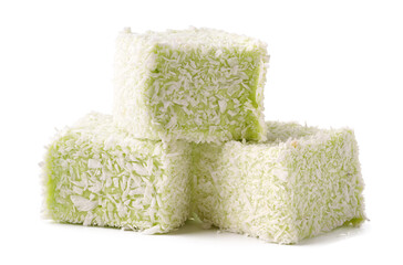 Dessert squares coated in coconut and flavored with green tea stacked on a white background