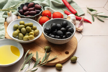 Black and green olives with olive oil, tomatoes, garlic and chili pepper on a wooden board