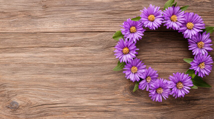 Fototapeta premium A beautiful circular wreath made of vibrant purple daisies rests on a rustic wooden background.