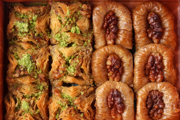 Delicious assortment of traditional pastries served in a wooden box with nuts and syrup
