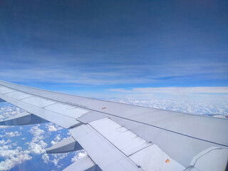 Fototapeta premium Stunning cloudscape seen from an airplane window during flight. Blue sky, white clouds and airplane wing. Aerial View of Cloudscape from Airplane Window