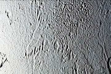A wall with a rough texture and a few scratches