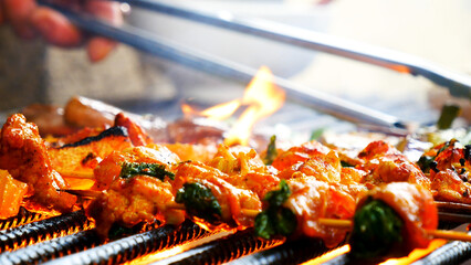 BBQ Barbecue grilled meat stick on fire flame with hot charcoal cooking outside. Beef grilling picnic outdoor with smoke bacon spicy sausage for party. Grill pork bbq on fire flame Party Concept