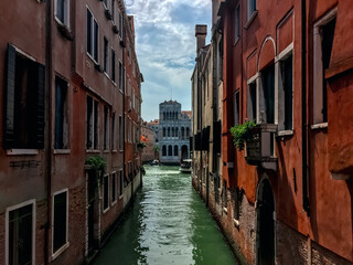 A Glimpse Down a Venetian Canal. A narrow canal winds its way through the city, lined with colorful buildings that lean in towards each other. 