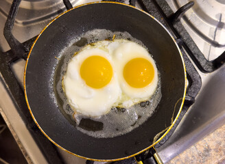 Two eggs are cooking in a pan on a stove