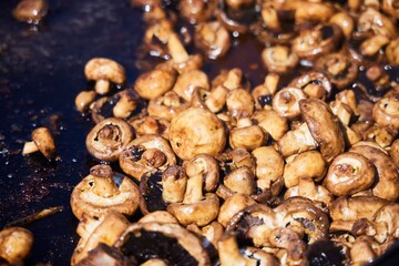 Various vegetables in a huge cauldron are cooked in oil.