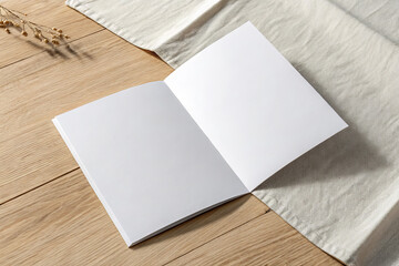 Blank open booklet on wooden surface with fabric