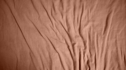 Photo of a fabric background. Uneven folds. More folds at the bottom of the background. Different shades. Mocha Mousse color. Color of the year 2025.
