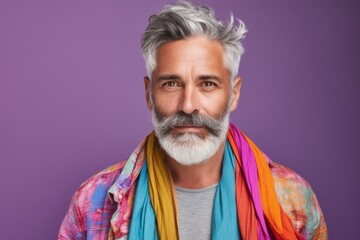 A man with a beard and gray hair is wearing a colorful scarf