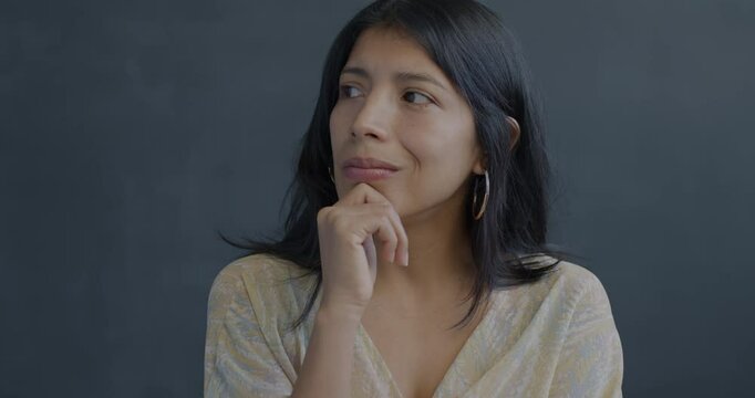 Portrait of creative Hispanic woman thinking raising finger having idea on black background. Problem solving and people concept.