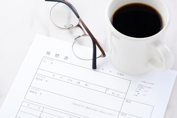 就職活動（就活）のために、コーヒーを飲みながら、履歴書を作成する
