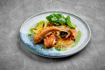 A vibrant and refreshing plate of grilled fish served with roasted vegetables and a side of sauce. The dish is served with roasted vegetables, creating a delightful contrast of textures