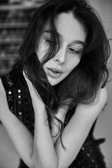 Fototapeta premium A woman with long hair is sitting on a chair. She is wearing a black vest and a black shirt