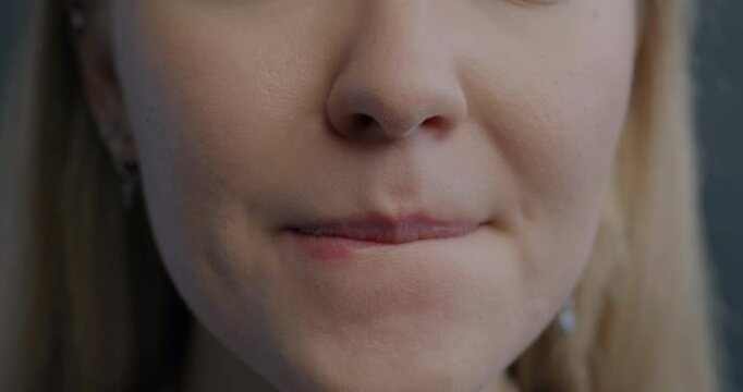 Close-up portrait of nervous young woman biting lips feeling unhappy on gray background. Negative emotion and human body part concept.
