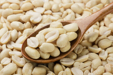 Peanuts in a wooden spoon close-up, background.