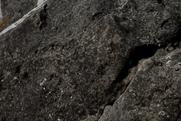 Black rock texture Rough mountain surface with cracks. Close-up. Stone background with space for design and text, backdrop wallpaper