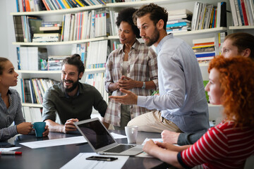 Smiling diverse colleagues gather in boardroom brainstorm discuss financial statistics together