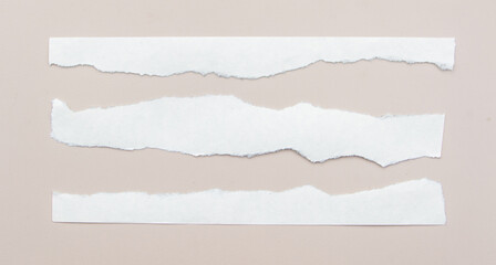 Fototapeta premium A collection of irregularly torn white papers scattered on a warm brown background, creating a textured and minimalistic aesthetic.