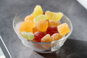 Bol en verre avec une variété de pâte de fruits, enrobés de sucre fin. Le bol est placé au soleil.