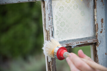 Painting a wooden vintage window outdoors, an eco-friendly re-use business.
