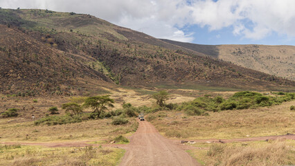 Safari jeeps crossing the Ngorongoro Conservation Area during rainy season in november in Tanzania, East Africa