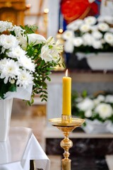 Bright yellow candle illuminates a tranquil altar adorned with white flowers in a serene setting