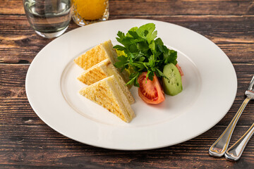 Toast with cheddar cheese and tomatoes and parsley on a white porcelain plate