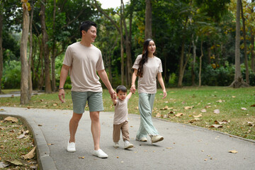 Young family walking along the path in a scenic park. Outdoor leisure and family bonding concept
