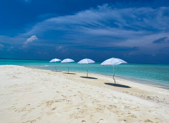 Summer tropical with white umbrella on the beach with  blue sky background