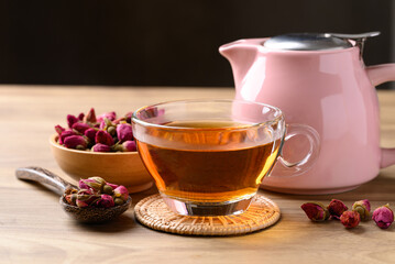 Rose tea in cup glass with dried rose bud and teapot on wooden and black, Healthy flower tea