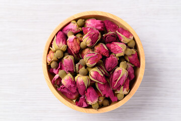 Dried rose bud tea in wooden bowl on white background, Healthy herbal tea