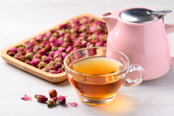 Rose tea in cup glass with dried rose bud and tepot on white background, Healthy flower tea