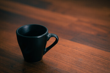 a small, dark-colored espresso cup sitting on a wooden surface