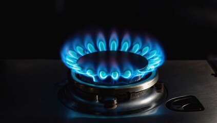 Blue gas flame burning on stovetop, dark background. Energy efficiency concept