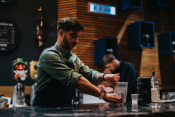 A professional bartender wearing an apron prepares drinks in a modern, stylish bar setting. The ambience reflects a cozy yet vibrant atmosphere with sophisticated decor and various drink-making tools.