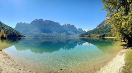 Obraz premium Serene Mountain Lake Landscape with Crystal Clear Water, Reflecting Peaks and Lush Greenery Under a Brilliant Blue Sky in a Picturesque Natural Setting