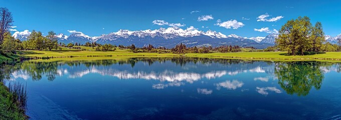 Fototapeta premium Serene Landscape of Tranquil Lake with Majestic Snow-Capped Mountains and Clear Blue Sky Reflecting in Calm Waters in a Picturesque Natural Setting