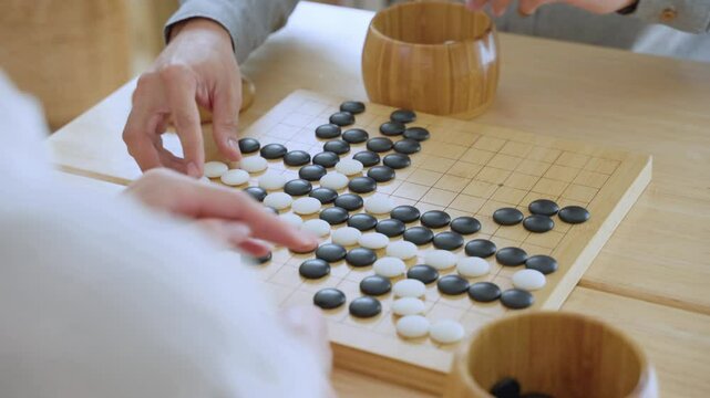 Close up of young men play board game Go during competition in community. 