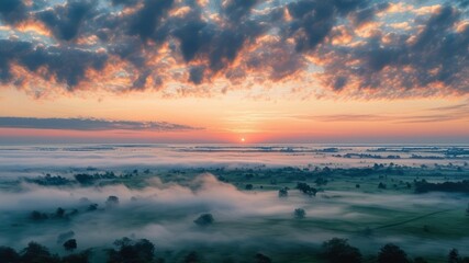 Fototapeta premium Serene sunrise over a misty landscape with rolling hills and clouds