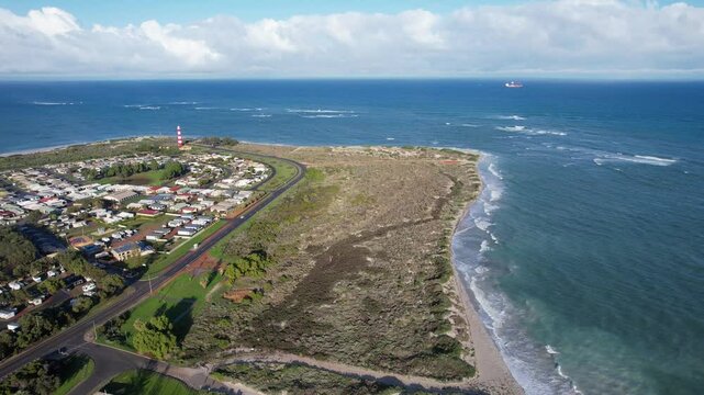 Aerial view of Point Moore Lighthouse overlooking a beautiful coastal landscape with homes and the ocean, Cervantes, Australia.
