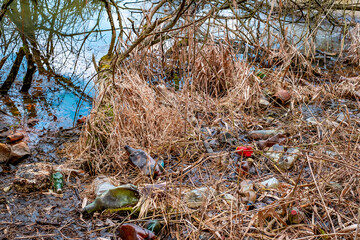 Various kinds of trash waste objects a lot floating in the pond mixed with aquatic plants